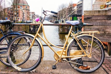 Amsterdam'da köprüde yaslanmış bisiklet