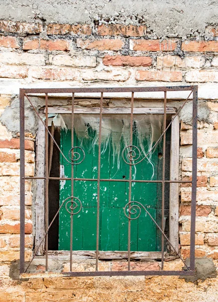 Groene luiken blok raam achter verroeste grill op onvoltooide br — Stockfoto