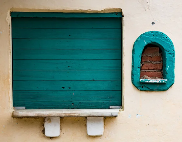 Dwa okna, jeden deskami z niebieski drewno i inne murowane — Zdjęcie stockowe