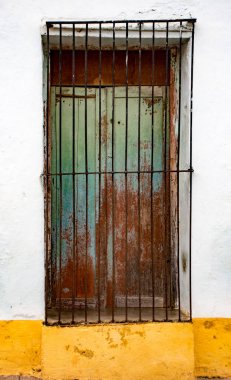 Beyaz ve sarı siyah demir çubuklarla yeşil kepenkli pencere 