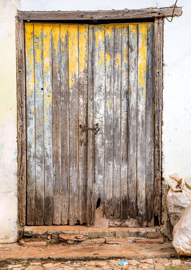 Unpainted tattered once-yellow door on white wall