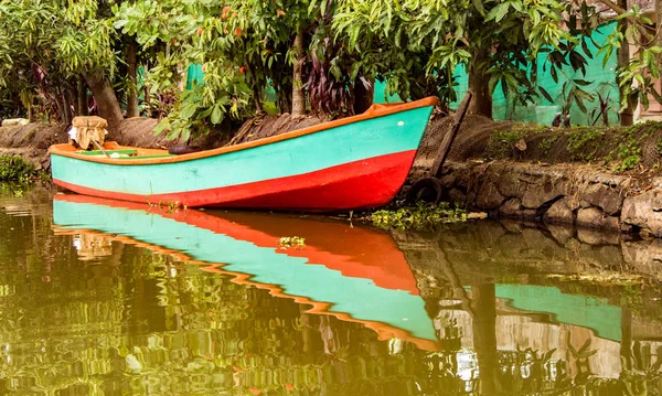 Petit bateau se trouve dans l'eau sous les arbres avec des reflets dans l'eau — Photo
