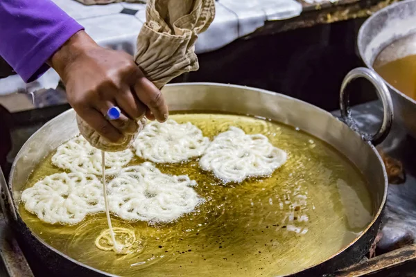 Hand gezien gieten gebak in hete olie voor een krakeling-achtige snack — Stockfoto
