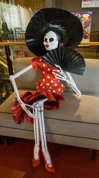 Oaxaca, Meksika - 2019-11-16 - Kadın iskeleti, dia de los muertos 'un yelpazesiyle sandalyede oturuyor