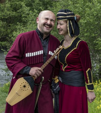 Mestia, Georgia - 11 Haziran 2016 - Geleneksel ortaçağ kıyafetleri içindeki kadın ve erkek bir müzik aleti tutarken güldüler