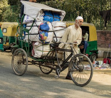Yeni Dehli, Hindistan, 19 Şubat 2018: Bisiklet üzerinde büyük bir yük taşıyan adam