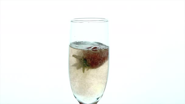 Бокал шампанского Крупный план - замедленная съемка две клубники опускаются в полный бокал — стоковое видео