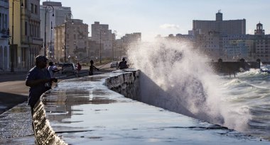 Havana, Küba - 19 Kasım 2011 - Duvarın üzerinden dalgalar geçerken körfezden balık avlamak için gençler beton bir duvara dizildiler