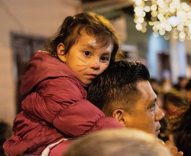 Cuenca, Ekvador - 2019-12-31 - Festivalde boyalı kedi beceren çocuklar babalarının omuzlarına biniyor