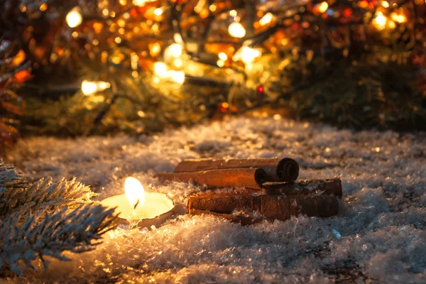 Tarçın ve mum arka plan bulanık ışık üzerinde karda. Renk tonlu.