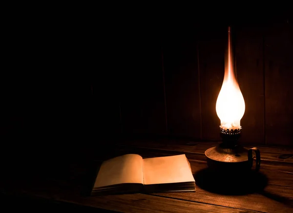 Libros antiguos con lámpara de parafina ardiendo cerca de la mesa de madera. Página en blanco —  Fotos de Stock