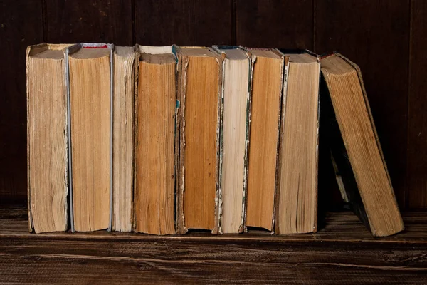 Old books stand in row on wooden table. — Stock Photo, Image