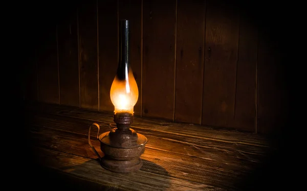 Lámpara de parafina quemada antigua cerca de la mesa de madera . Fotos de stock