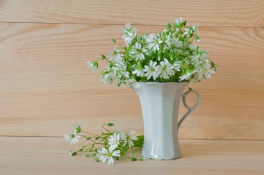 Bouquet of white wild flowers of stellaria holostea in a cup on  clipart