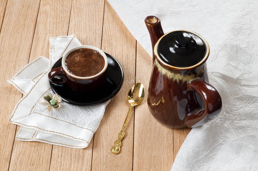 Coffee in a dark porcelain cup on a wooden table