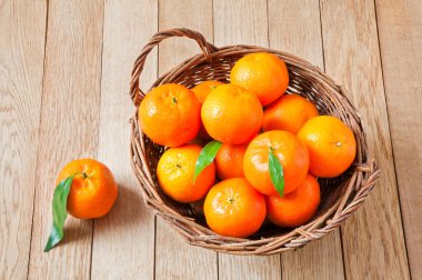 Tahta bir sepetin içindeki taze organik mandalinalar.