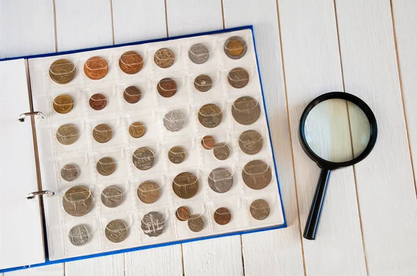 Pagina van numismatiek album met verschillende munten op een wit houten — Stockfoto