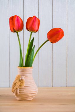 Masadaki vazoda duran bir buket kırmızı lale. Hayat dolu
