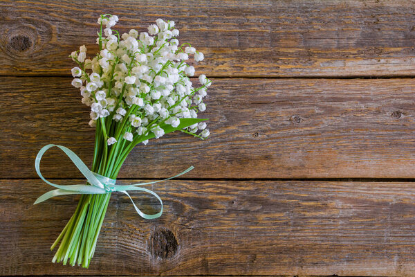 Beautiful bouquet of white lily of the valley flowers on a wooden tabl
