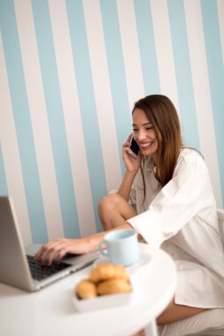 Dizüstü bilgisayar ve telefon kullanan mutlu kadın