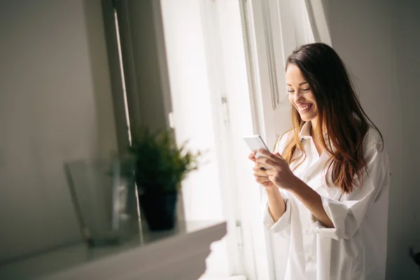 Mulher bonita usando telefone em casa — Fotografia de Stock