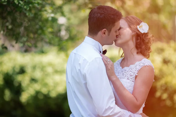Mooie bruid en bruidegom kussen buitenshuis — Stockfoto