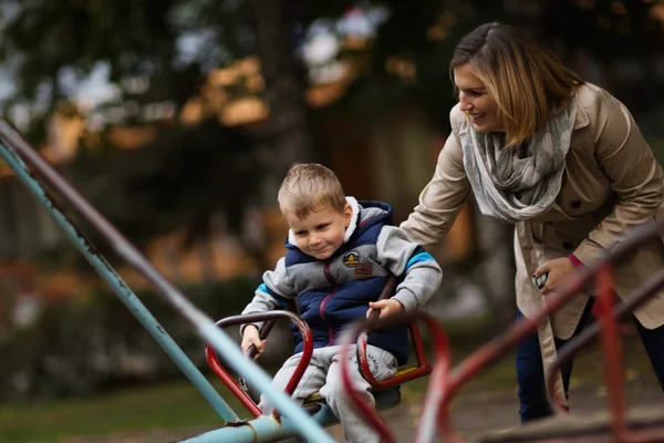 Anne ile oğlu caraousel üzerinde oynama — Stok fotoğraf