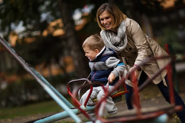 Madre giocare con figlio su caraousel — Foto Stock