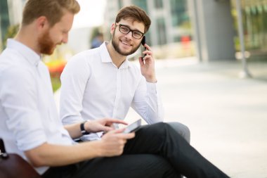 İşadamları bankta otururken konuşuyor