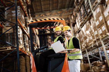 İşçiler depoda teknoloji forklift kullanma