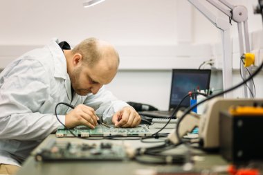 Technician fixing motherboard by soldering clipart