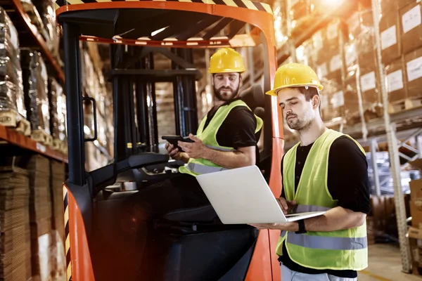 Werknemers die gebruikmaken van technologie heftruck in het magazijn — Stockfoto