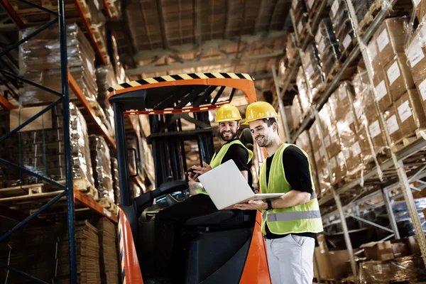 Lavoratori che utilizzano carrelli elevatori tecnologici in magazzino — Foto Stock