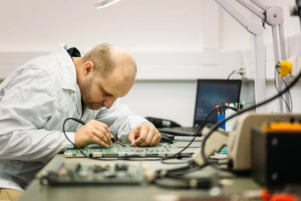 Técnico fixando placa-mãe por solda — Fotografia de Stock