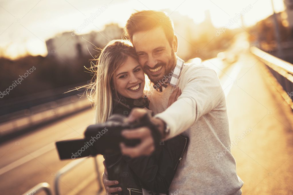 Happy couple taking selfies in city