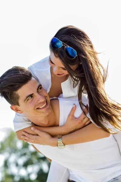 Bonito homem alegre carregando sua namorada piggyback — Fotografia de Stock