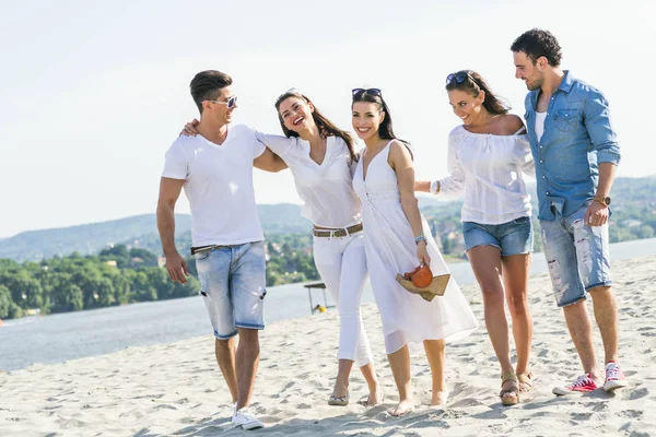 Grupp av unga människor höll händerna på stranden — Stockfoto