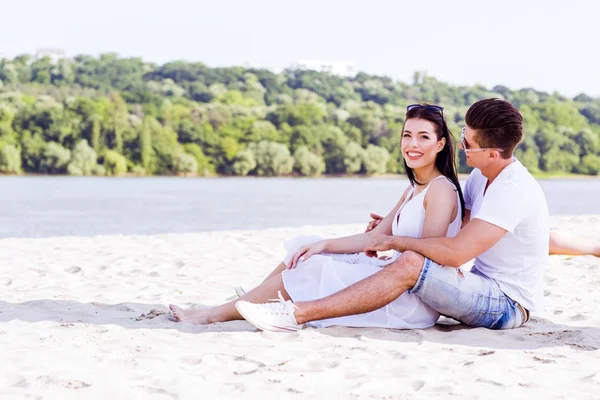 Romantiska unga paret sitter vid en strand — Stockfoto