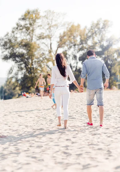 Coppia che si tiene per mano e cammina su una spiaggia — Foto Stock