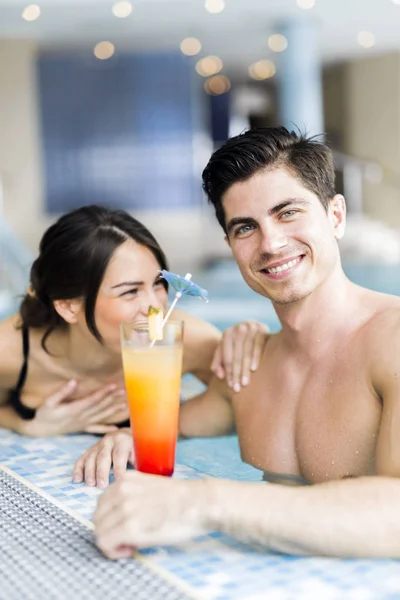 Ritratto di una coppia che sorride e beve un cocktail in piscina — Foto Stock