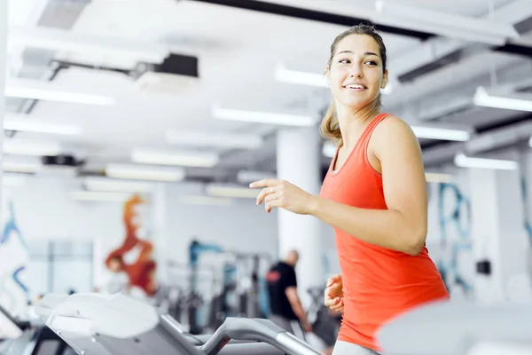 Beautiful young woman running on a treadmill in gym — Stock Photo, Image