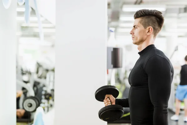 Joven hombre guapo haciendo ejercicio en un gimnasio — Foto de Stock