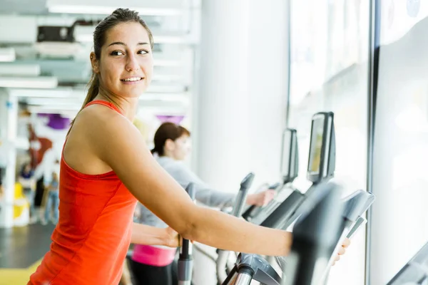 Mujer en forma joven usando un entrenador elíptico — Foto de Stock