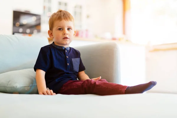 Счастливый мальчик сидит на диване в гостиной — стоковое фото