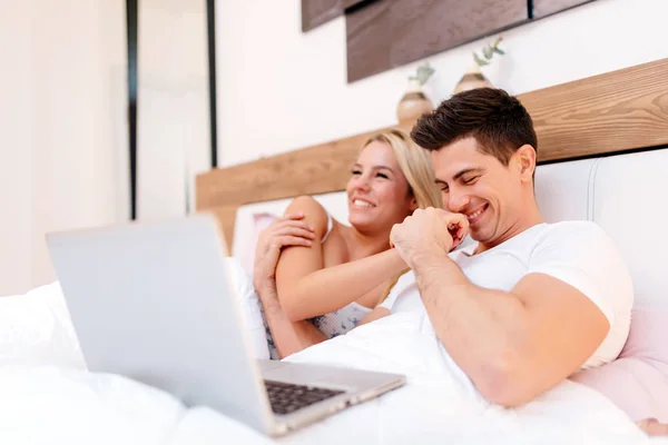 Bella coppia utilizzando il computer portatile a letto — Foto Stock
