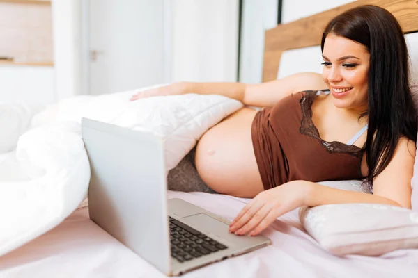 Schwangere benutzt Laptop im Bett — Stockfoto