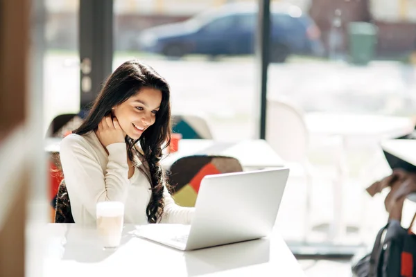 Brunette utilisant un ordinateur portable dans un café — Photo