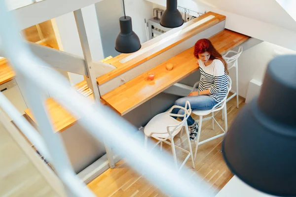 Hermosa mujer sentada en el mostrador en casa —  Fotos de Stock