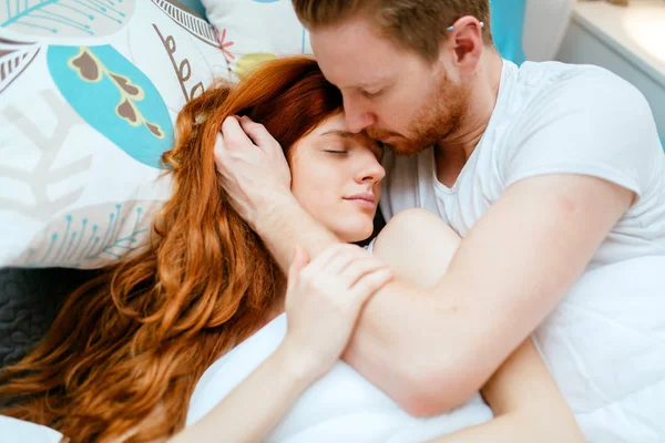 Pareja enamorada abrazándose besándose en la cama — Foto de Stock