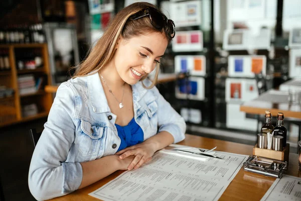 Bella bruna che guarda attraverso il menu — Foto Stock